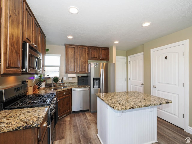 879 W Saddlebrook Dr, Kaysville, UT 84037 - kitchen with stainless steel appliances, dark wood-style floors, a kitchen breakfast bar, a sink, and stone countertops
