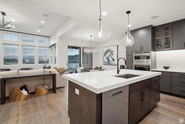 kitchen featuring a sink, appliances with stainless steel finishes, light countertops, open floor plan, and recessed lighting