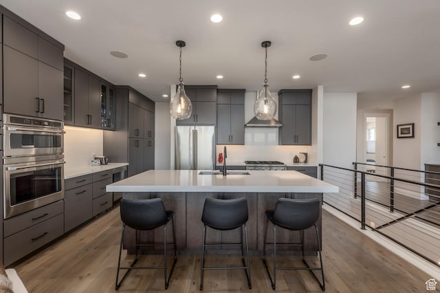 kitchen featuring appliances with stainless steel finishes, a sink, a kitchen bar, light countertops, and light wood-style floors