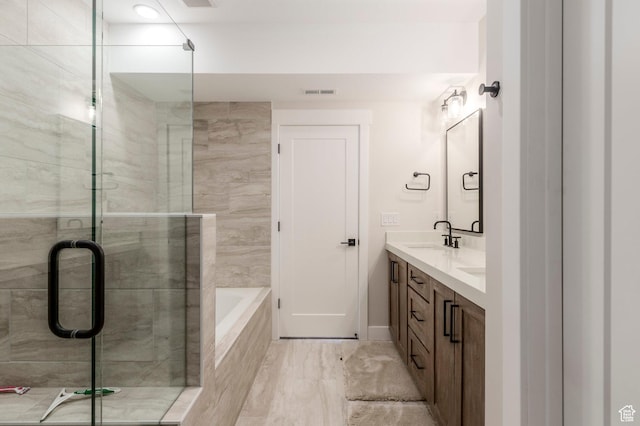 bathroom featuring a shower stall, double vanity, baseboards, and tiled tub