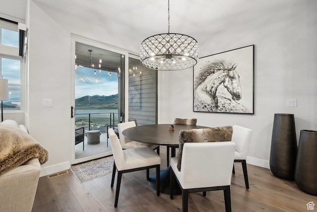 dining room with healthy amount of natural light, a chandelier, and wood finished floors