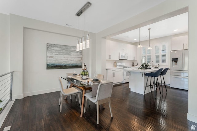 dining area with dark wood finished floors, baseboards, and recessed lighting