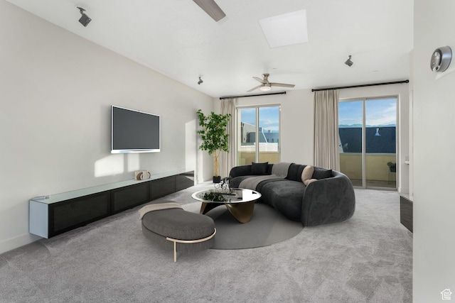 living room with ceiling fan, a skylight, and carpet flooring