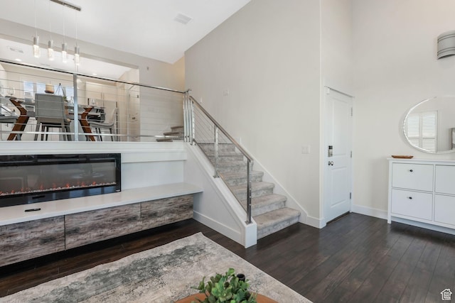 staircase with wood finished floors, baseboards, and a towering ceiling