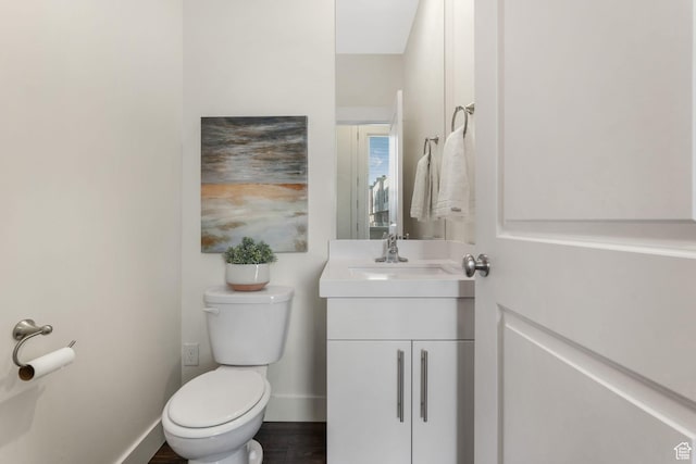 half bath with toilet, vanity, and baseboards