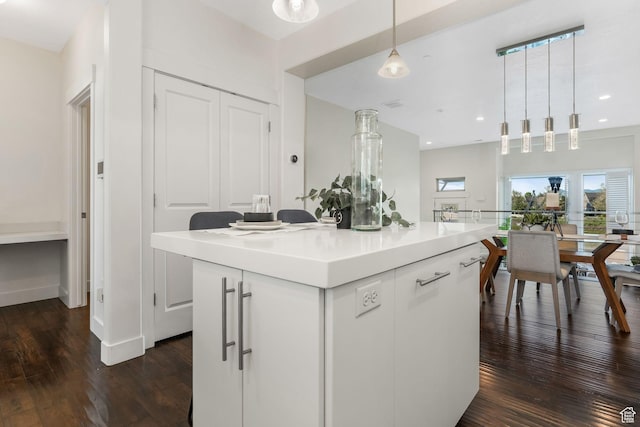 kitchen with dark wood-style flooring, pendant lighting, light countertops, a center island, and white cabinets