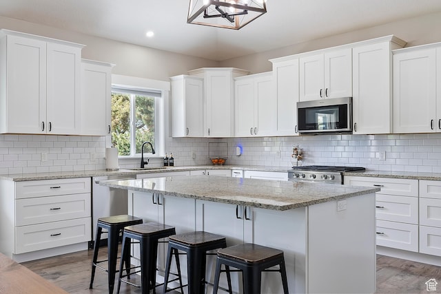 2685 N 850 E, North Ogden, UT 84414 - kitchen with stainless steel appliances, a sink, a center island, a breakfast bar, and white cabinets
