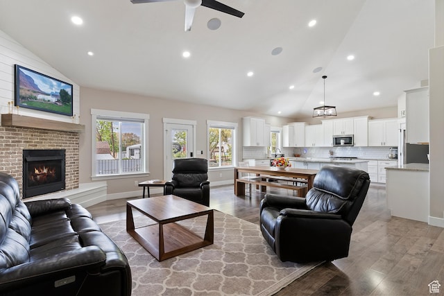2685 N 850 E, North Ogden, UT 84414 - living area featuring a ceiling fan, high vaulted ceiling, light wood-type flooring, a brick fireplace, and recessed lighting
