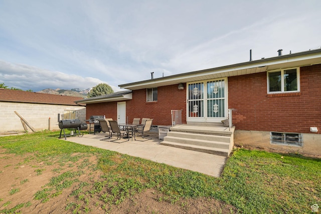 rear view of property featuring brick siding, a patio, and a yard