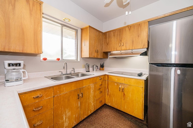 kitchen featuring freestanding refrigerator, under cabinet range hood, a sink, electric stovetop, and light countertops