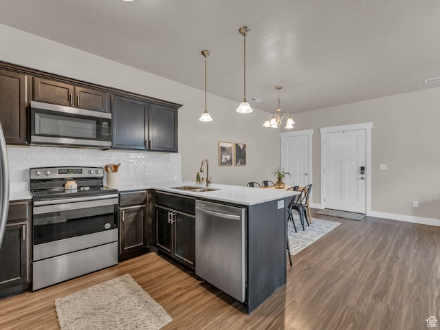 14642 S Mckellen Dr Unit 201, Herriman, UT 84096 - kitchen with appliances with stainless steel finishes, a sink, light wood finished floors, backsplash, and a peninsula