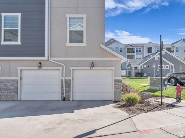 14642 S Mckellen Dr Unit 201, Herriman, UT 84096 - multi unit property with stone siding, a residential view, driveway, a garage, and stucco siding