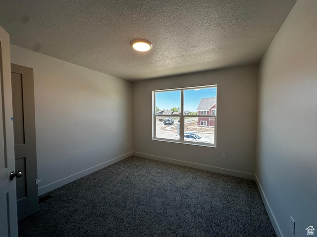 carpeted empty room with a textured ceiling and baseboards