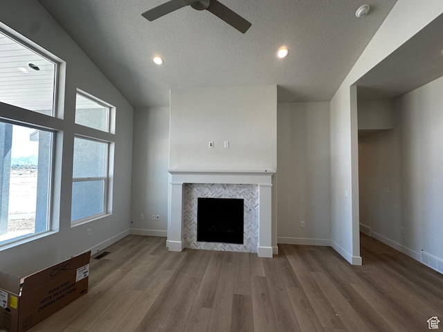 unfurnished living room featuring ceiling fan, a fireplace, wood finished floors, vaulted ceiling, and baseboards