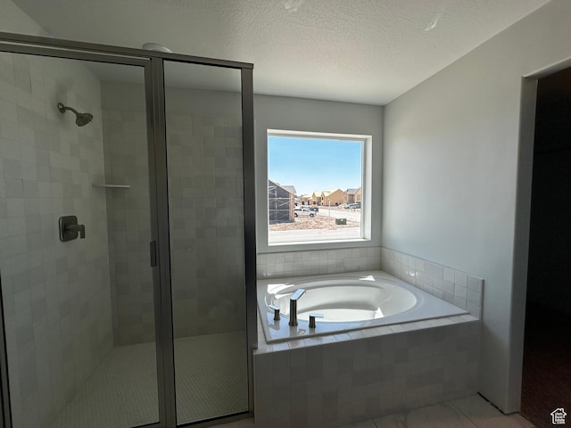 bathroom featuring a stall shower, a garden tub, a textured ceiling, and tile patterned flooring