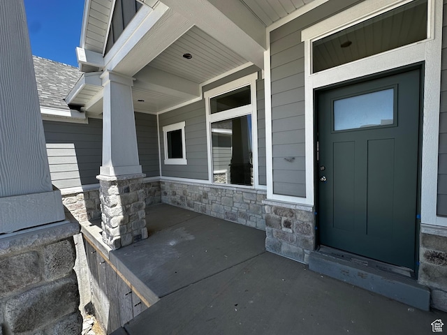 entrance to property with a porch and stone siding