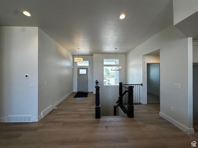 foyer entrance with wood finished floors, baseboards, recessed lighting, a textured ceiling, and a chandelier