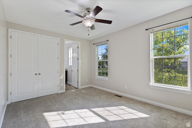 unfurnished bedroom featuring carpet, a closet, baseboards, and ceiling fan