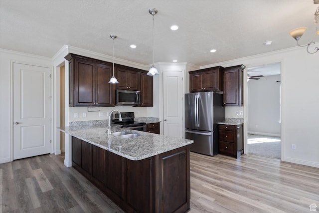kitchen featuring stainless steel appliances, light wood-style flooring, dark brown cabinetry, crown molding, and a sink