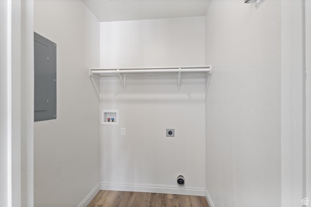 laundry area with electric panel, hookup for an electric dryer, hookup for a washing machine, wood finished floors, and baseboards