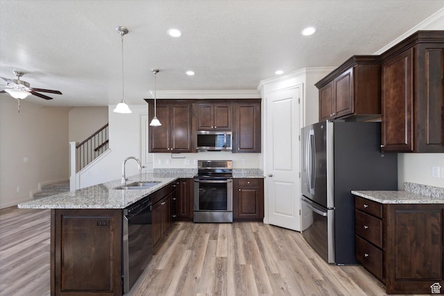 kitchen with appliances with stainless steel finishes, a sink, a peninsula, light wood finished floors, and a textured ceiling