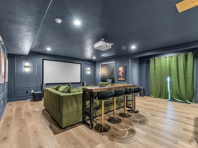 home theater room featuring a decorative wall, light wood-style floors, and recessed lighting