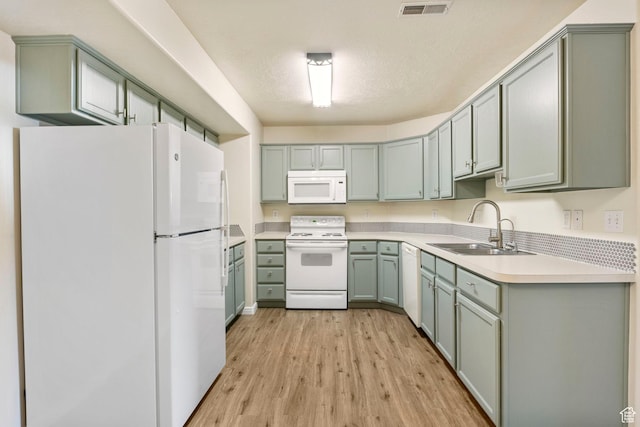 kitchen with white appliances, a sink, light wood-style flooring, light countertops, and gray cabinets