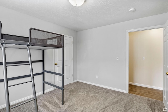unfurnished bedroom with carpet, a textured ceiling, and baseboards