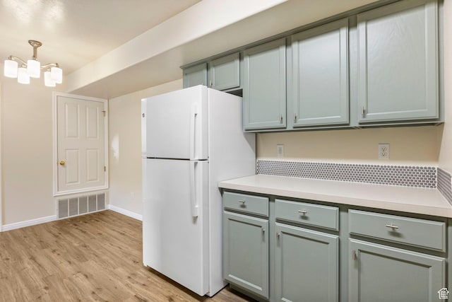 kitchen with freestanding refrigerator, light countertops, light wood finished floors, baseboards, and gray cabinetry