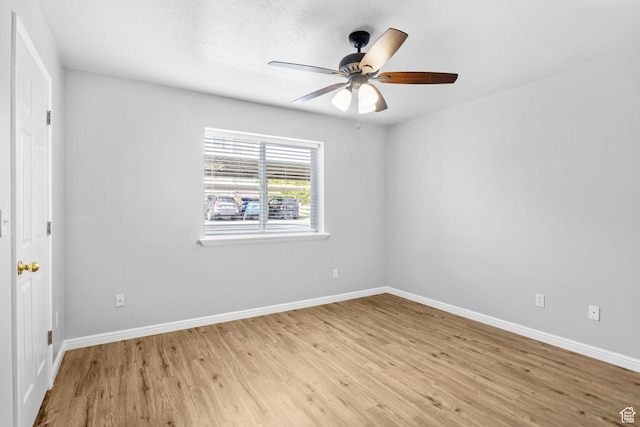spare room featuring light wood-type flooring, baseboards, and a ceiling fan