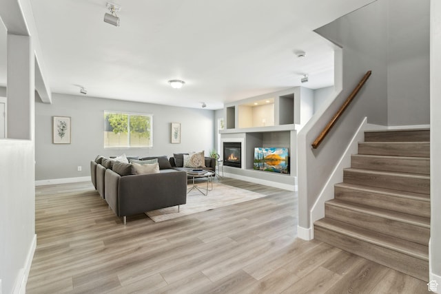 8392 S Oak Vista Dr, West Jordan, UT 84081 - living area featuring baseboards, a glass covered fireplace, stairs, and light wood-style floors