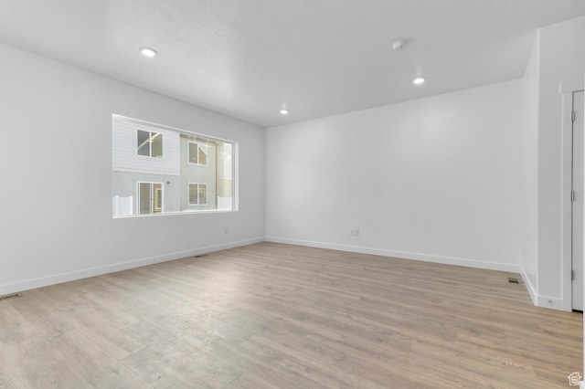 spare room with light wood-style floors, baseboards, and recessed lighting