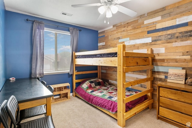 carpeted bedroom with wood walls and a ceiling fan