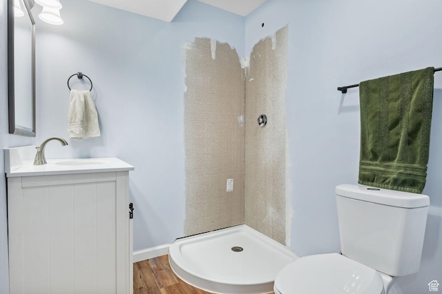bathroom with toilet, a shower stall, vanity, and wood finished floors