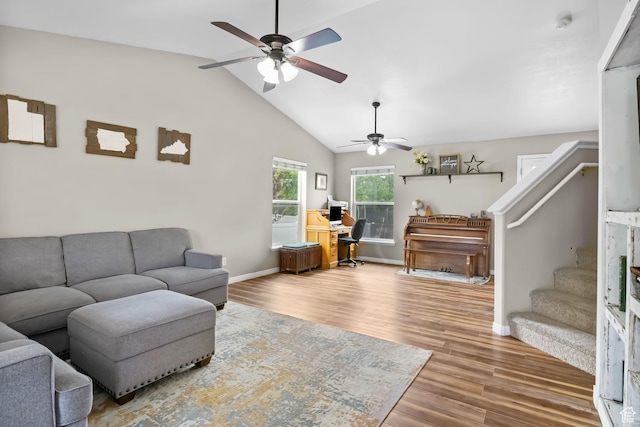 living area with a ceiling fan, stairs, baseboards, wood finished floors, and lofted ceiling
