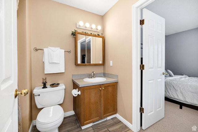 ensuite bathroom with vanity, toilet, and baseboards
