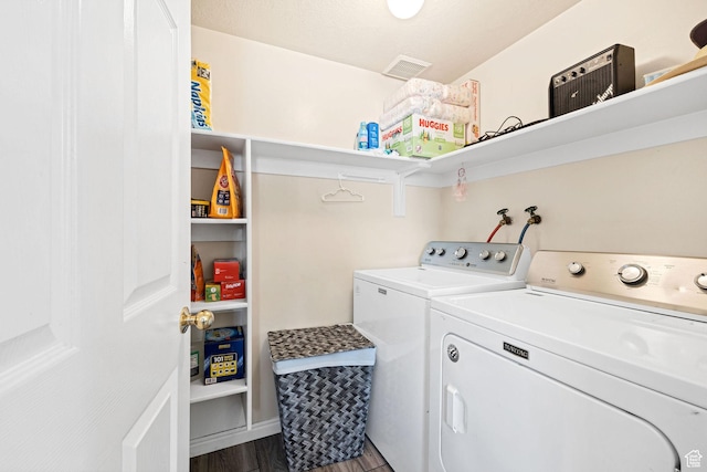 clothes washing area with washing machine and clothes dryer and dark wood finished floors
