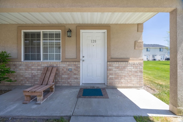 property entrance featuring stucco siding and brick siding