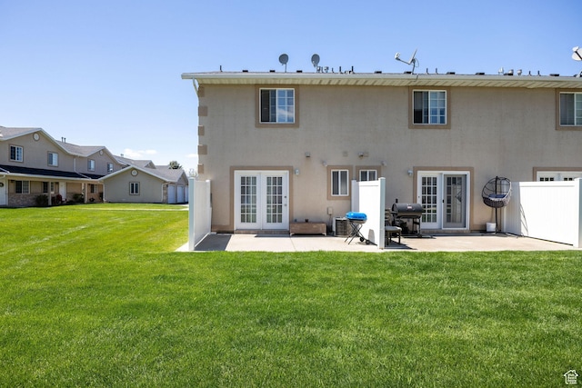rear view of property featuring a patio area, french doors, a yard, and stucco siding