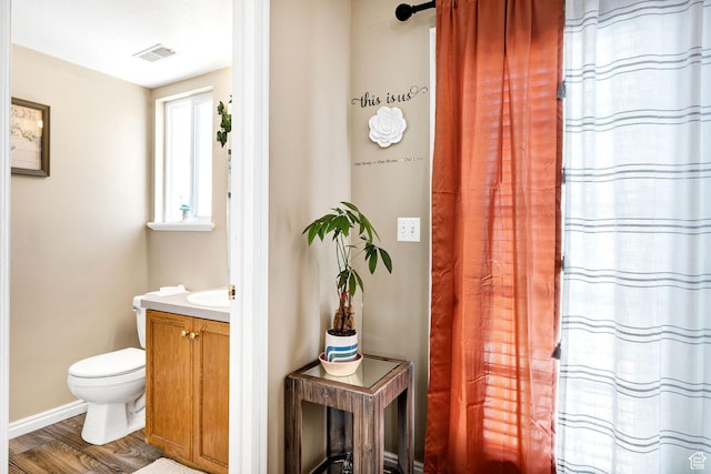 bathroom with wood finished floors, vanity, toilet, and baseboards