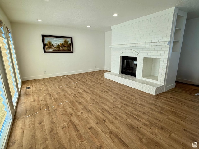 9977 S Lannae Dr E, Sandy, UT 84094 - unfurnished living room featuring wood finished floors, recessed lighting, baseboards, and a brick fireplace