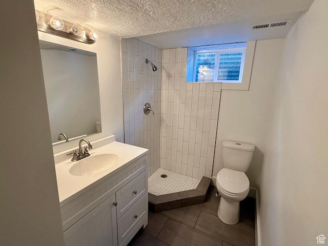 9977 S Lannae Dr E, Sandy, UT 84094 - bathroom with toilet, vanity, a textured ceiling, a tile shower, and tile patterned floors
