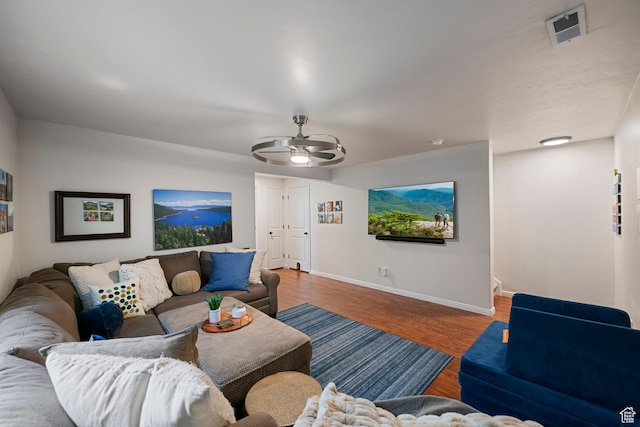 living room featuring baseboards, ceiling fan, and wood finished floors