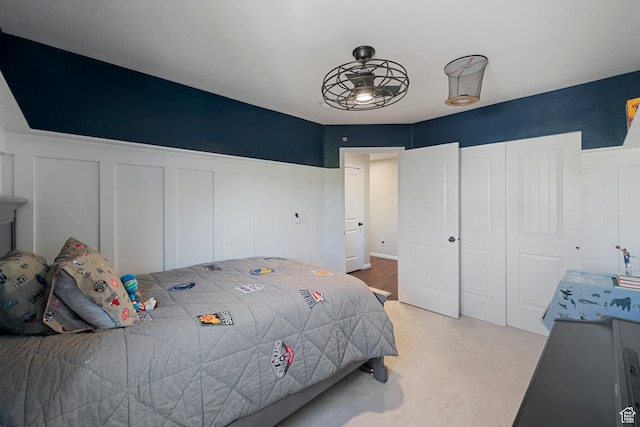 bedroom featuring a decorative wall, wainscoting, light carpet, and a closet