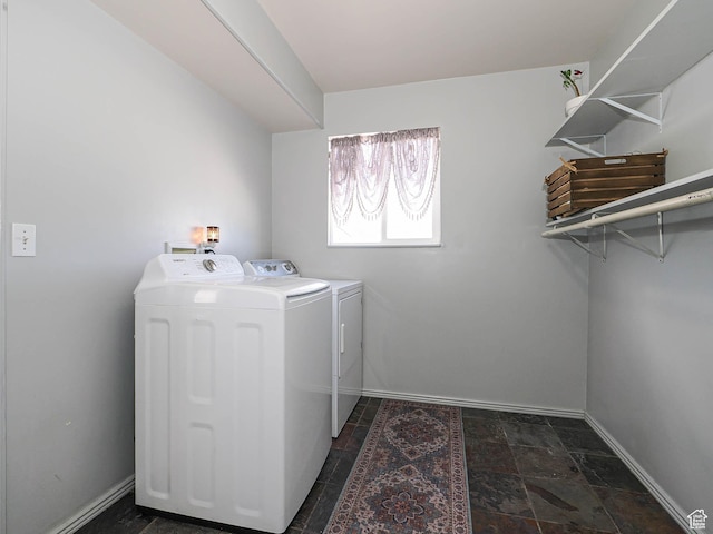 washroom with washer and clothes dryer, baseboards, and dark stone finish floors