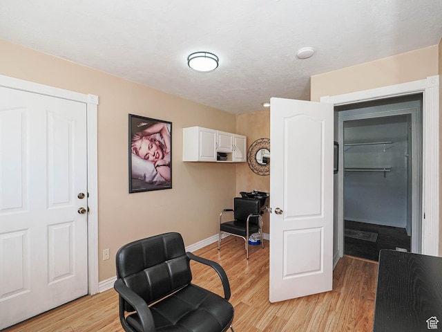 sitting room with light wood-type flooring, baseboards, and an office area