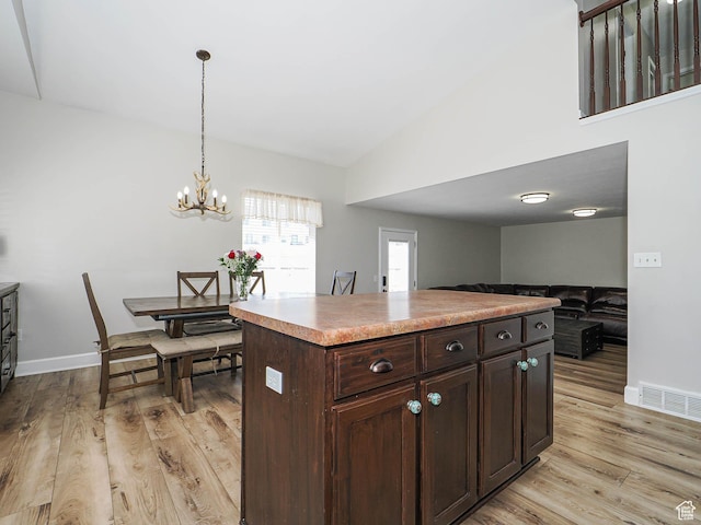 kitchen with light wood finished floors, dark brown cabinets, vaulted ceiling, a chandelier, and decorative light fixtures