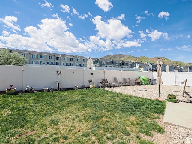 view of yard with a residential view, a mountain view, and a patio