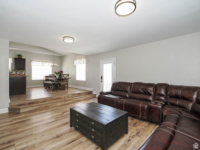 living room with a chandelier, light wood-type flooring, and baseboards