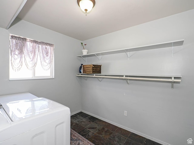 laundry area with washing machine and clothes dryer, dark stone finish flooring, and baseboards
